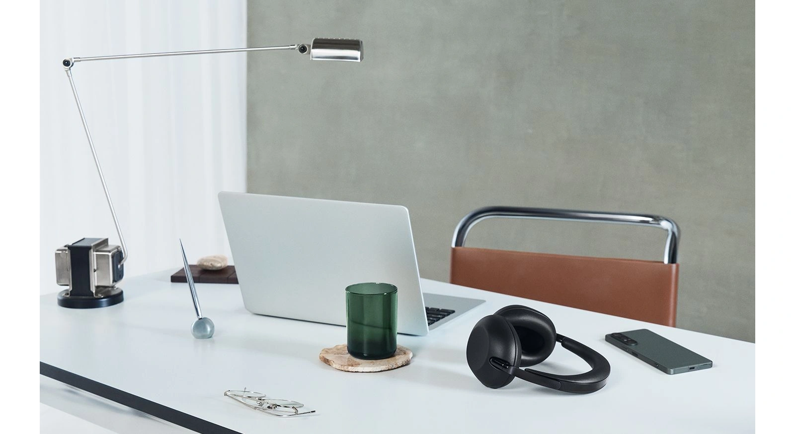 Черные наушники Sony 1000X THE COLLEXION на белом столе рядом с телефоном и ноутбуком