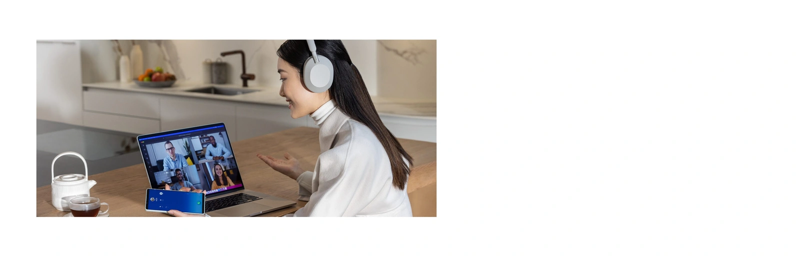 Девушка на видеозвонке с ноутбуком и смартфоном в наушниках Sony WH-1000XM5