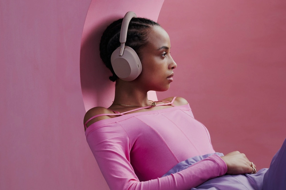 Девушка в наушниках Sony WH-1000XM5 дымчато-розового цвета