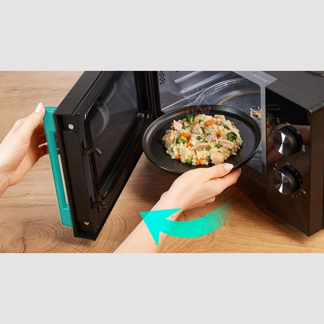 Руки достают тарелку с блюдом из чёрной микроволновой печи Gorenje
