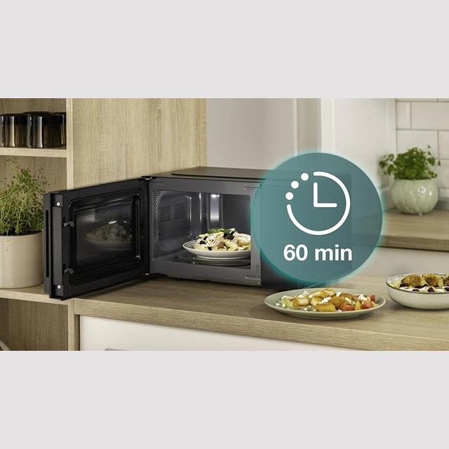 Рука ставит тарелку в открытую микроволновая печь Gorenje, обозначение таймера 60 минут