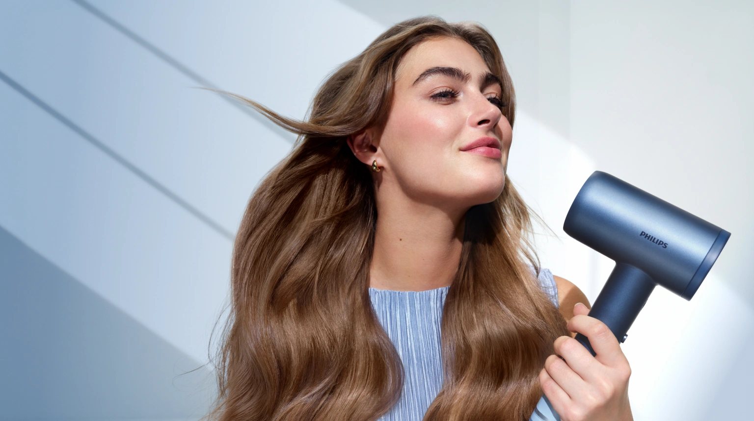 Женщина сушит волосы феном Philips Aqua SenseIQ серии 9000