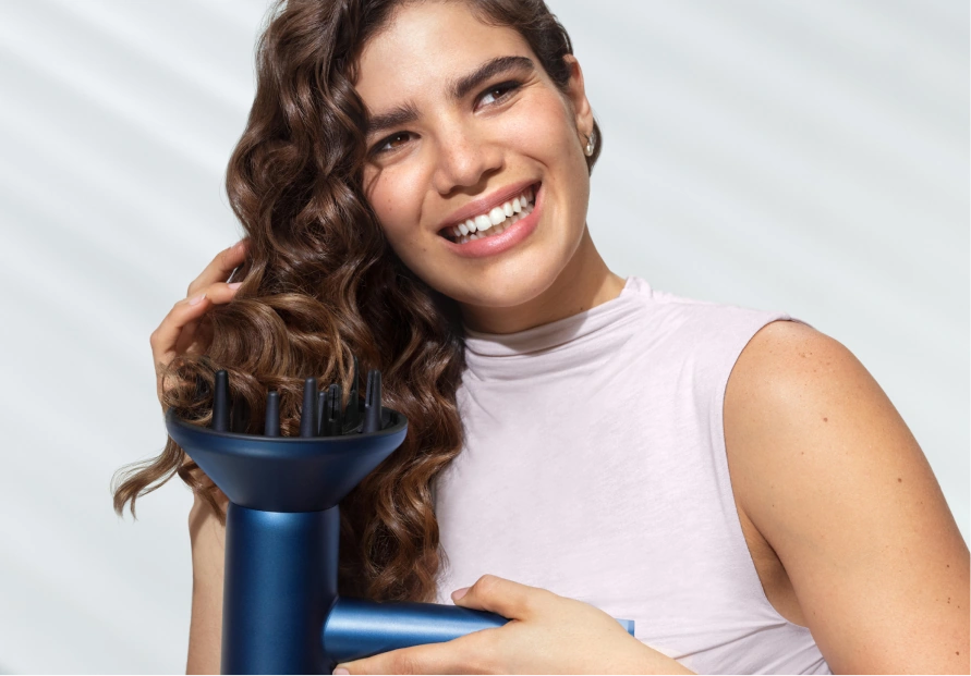 Женщина сушит кудрявые волосы феном Philips с диффузором