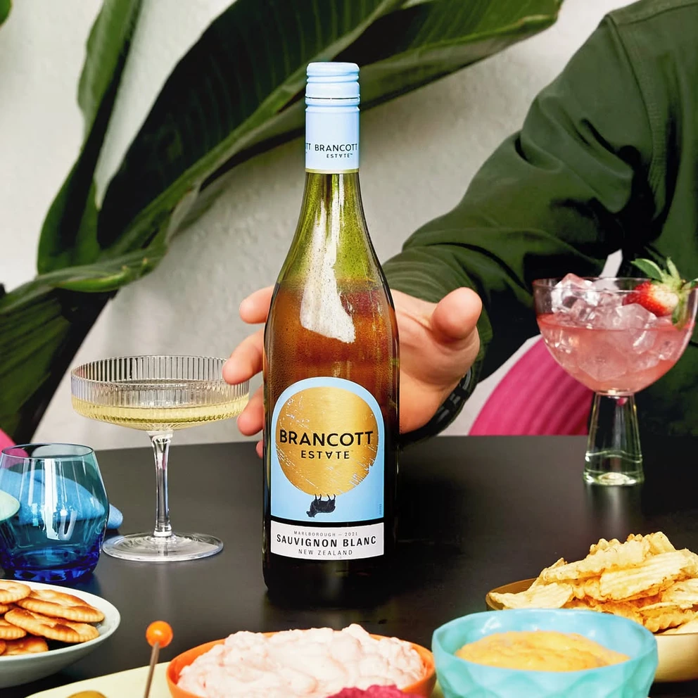 Пляшка Brancott Estate Sauvignon Blanc на столі з коктейлями та закусками