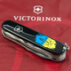 Складаний швейцарський ніж Victorinox Vx13713.3_T1026u Huntsman Ukraine 15 функцій 91 мм Трезубець фігурний на фоні прапора - зображення 2